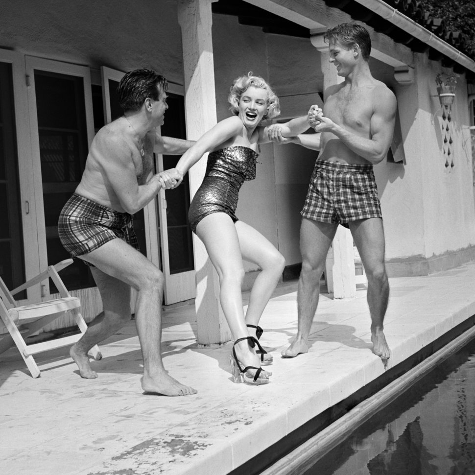 Marilyn Monroe (1926-1962) wearing heels and a bathing suit, plays around w...